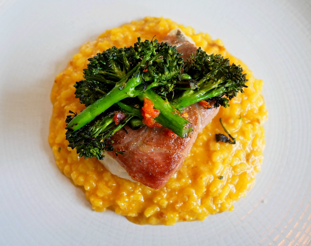 Roasted Hake wrapped in Serrano Ham, with a Saffron and Chorizo Risotto with Chargrilled Brocolli